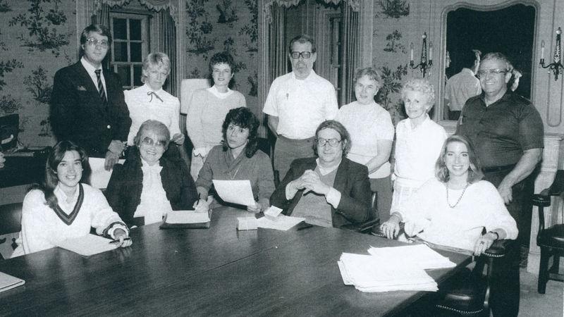 一群人围坐在一张桌子旁的黑白照片.